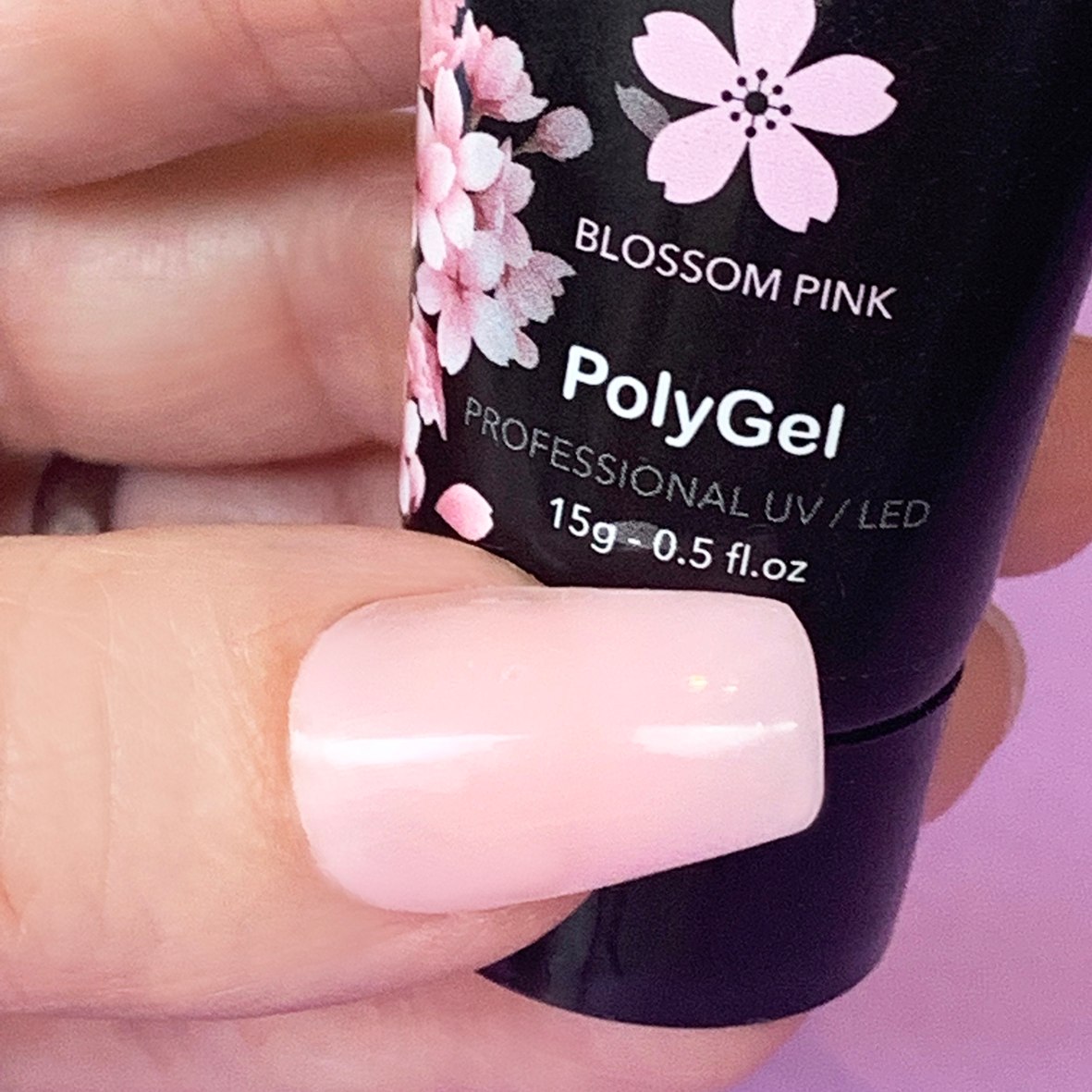 Close-up of a manicured nail next to a Zekaio Blossom Pink PolyGel tube