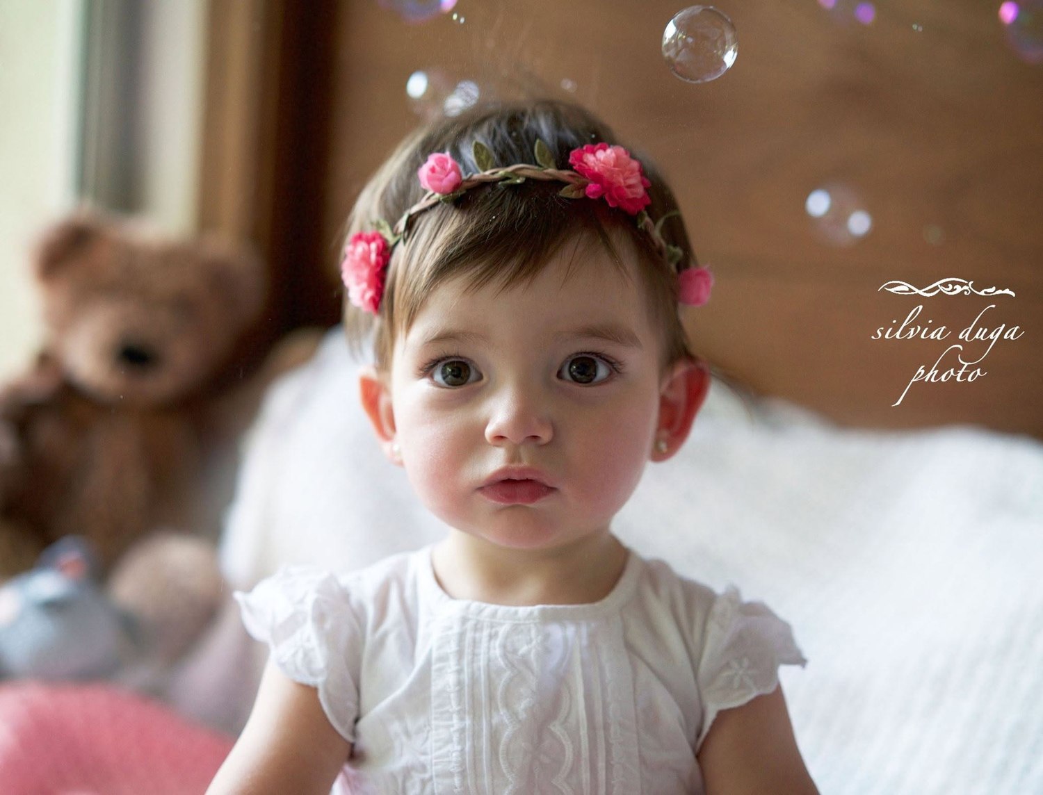 Toddler wearing a flower crown with soap bubbles floating around