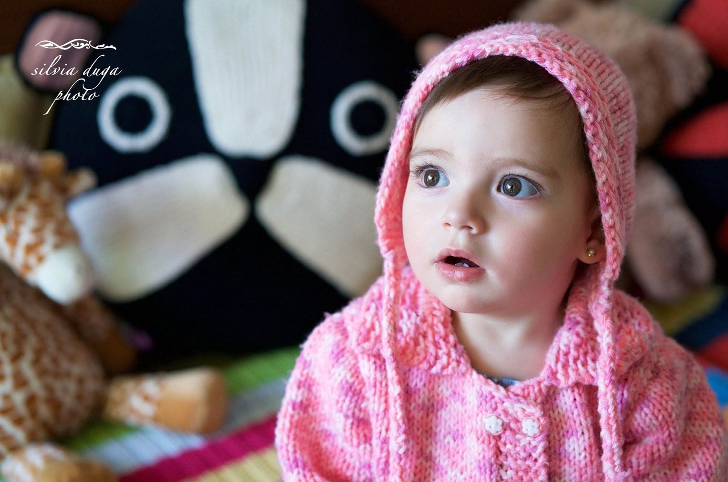 Toddler wearing a pink knit bonnet with wide eyes