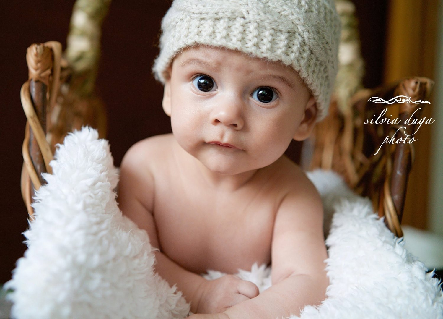 Baby wearing a knit hat wrapped in a white blanket