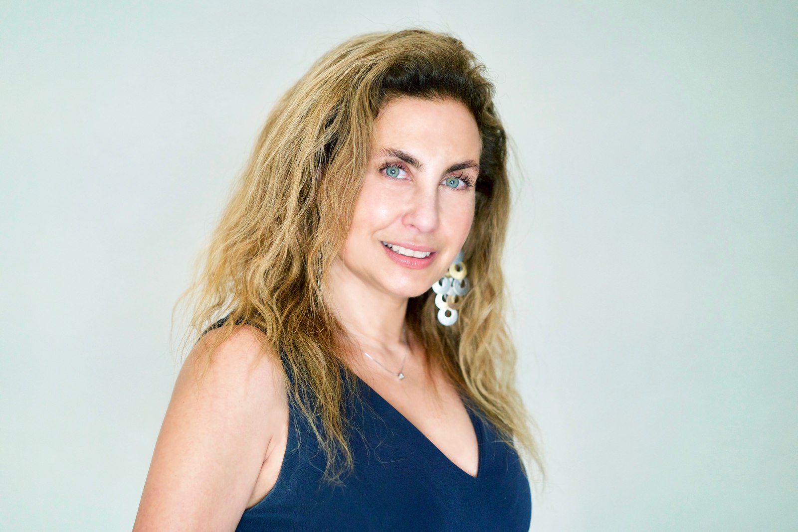 Corporate headshot of a smiling woman with long hair and statement earrings
