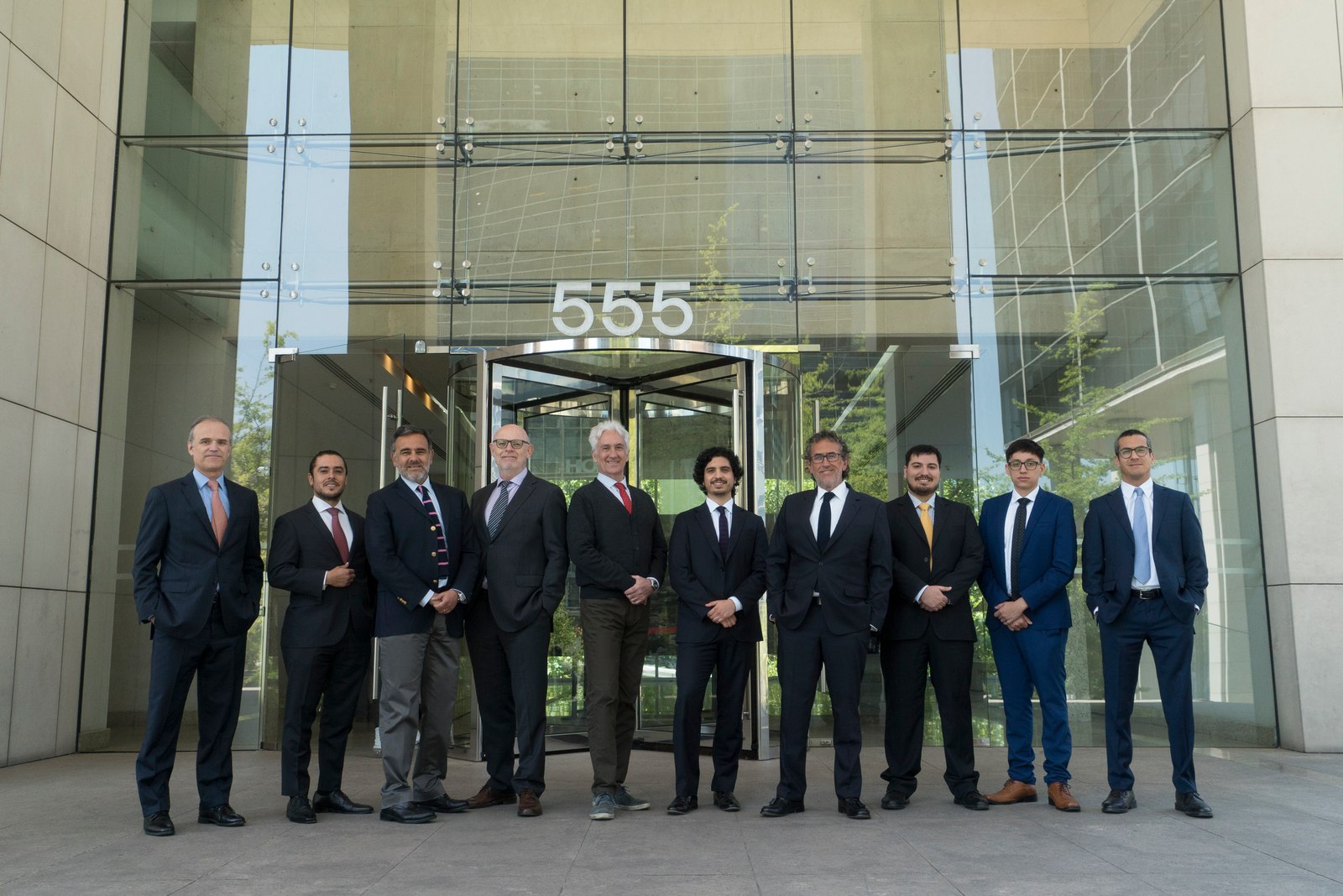 Group of colleagues from 555 Abogados standing outside their office building entrance