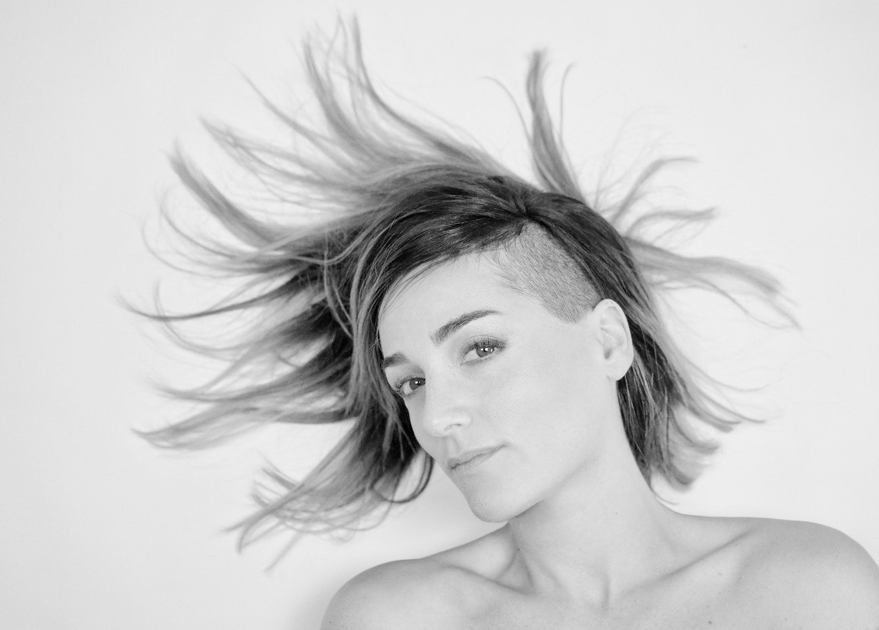 Black and white portrait of a woman with hair in motion, lying down