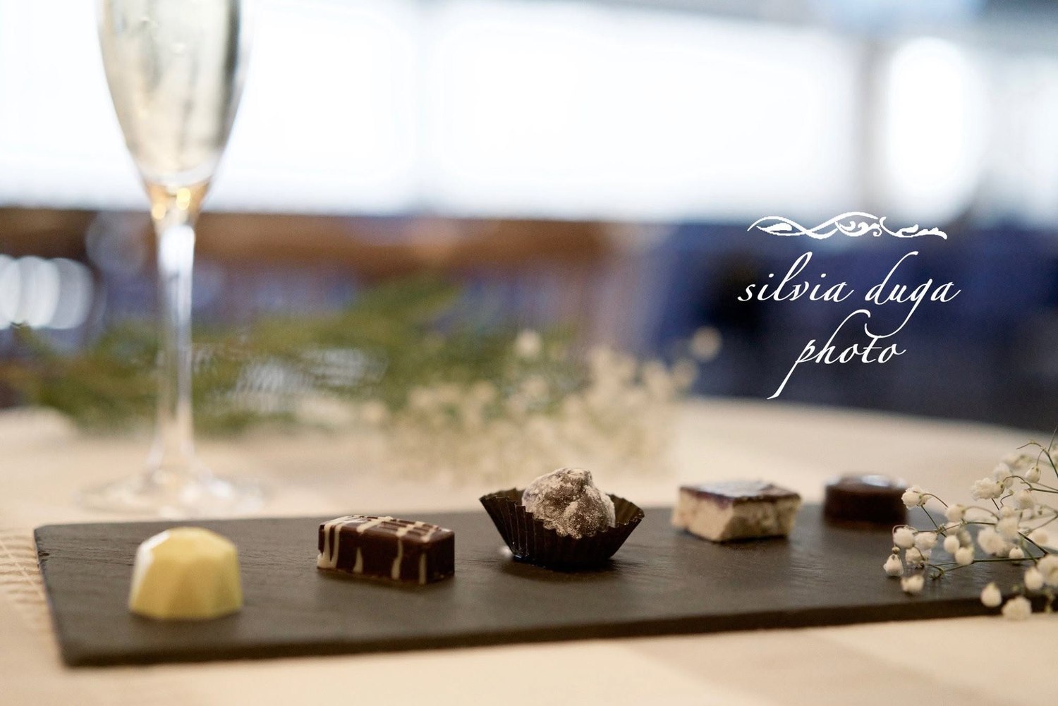 Assortment of chocolates on a slate board with a glass of champagne